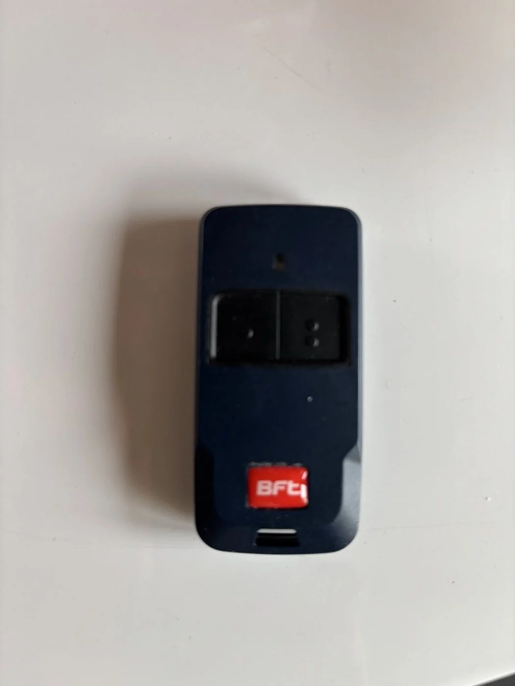 Garage remote · red BFT label at bottom · upper-left one-dot button
